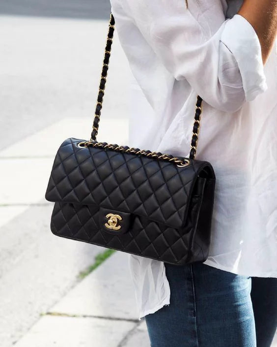 Woman in a white shirt and denim jeans wearing a black chanel classic flap shoulder bag